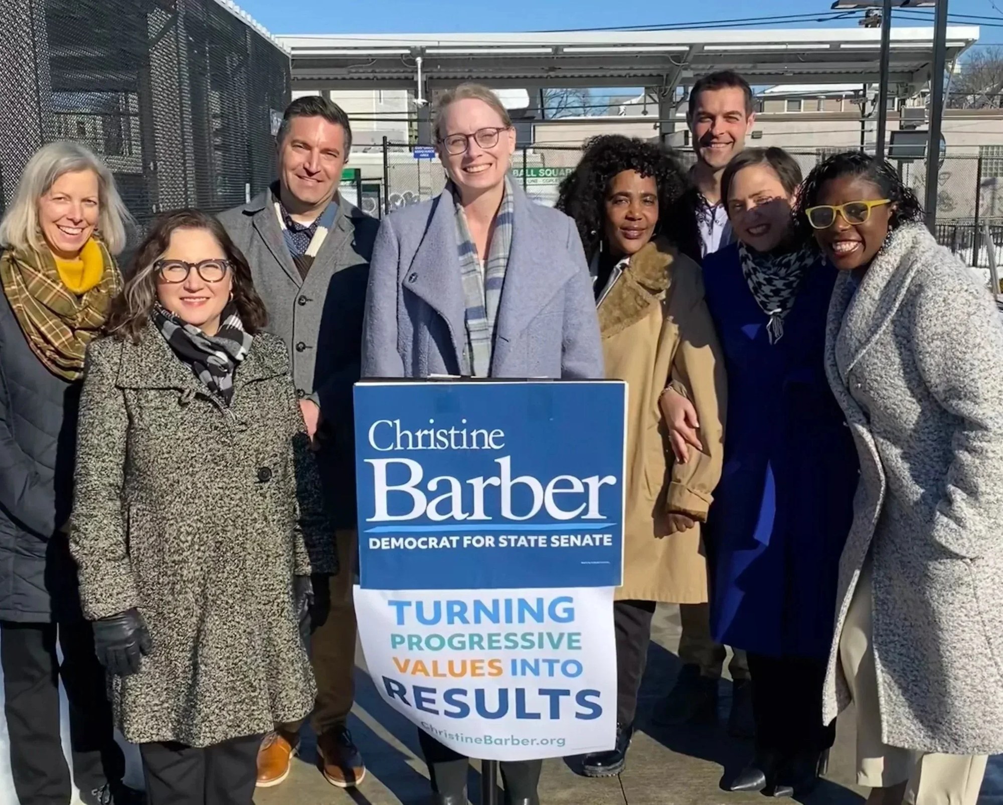 Christine Barber with supporters at a campaign event, holding a Turning Progressive Values Into Results sign